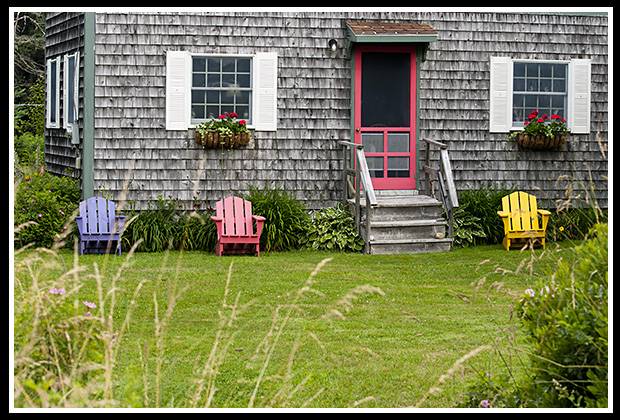 colorful chairs around a wooden shingled house