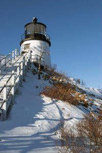 Historic Owl's Head Lighthouse sits on a snow covered cliff in Maine.