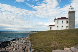 Watch Hill Lighthouse along rocky shoreline in Rhode Island.