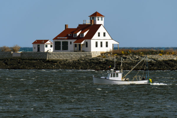 Lobster boat passes by the Wood Island Lifesaving Station, also referred to as Jerry’s Point Lifesaving Station, under restoration, on Wood Island, in southern Maine, during rough seas. Lifesaving stations coordinated with lighthouse keepers to aid in offshore rescues.