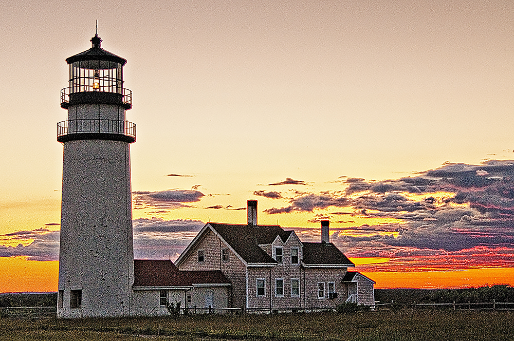 Sun sets behind Cape Cod (Highland) Lighthouse in Massachusetts.