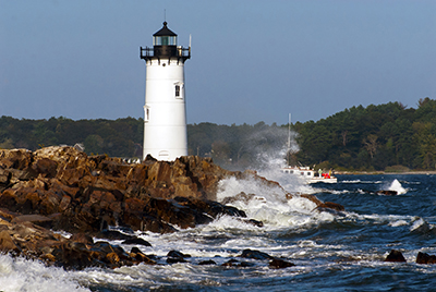 Portsmouth Harbor lighthouse guides fishing boat through dangerous surf.