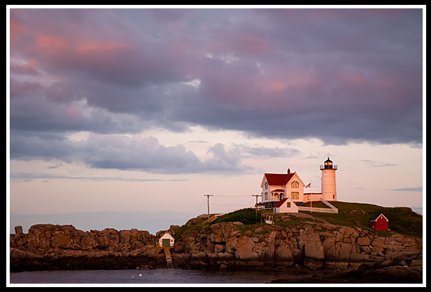 Storm clouds approach as sun set by Cape Neddick light
