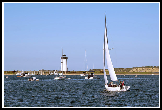 sailboat comes in Edgartown Harbor by lighthouse