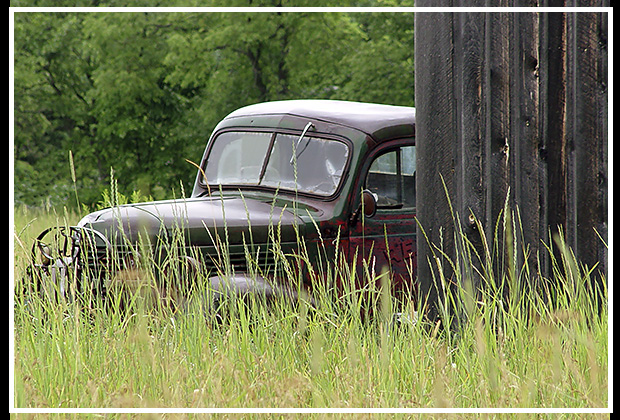 car by old barn