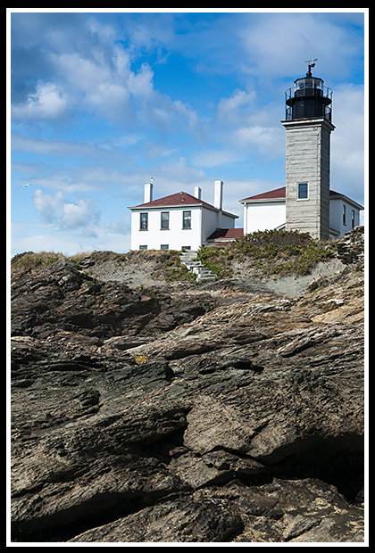 Beavertail Lighthouse tower and musuem over rocky shore 