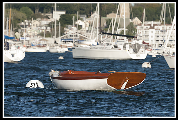 wooden boat among sailboats in Newport Harbor