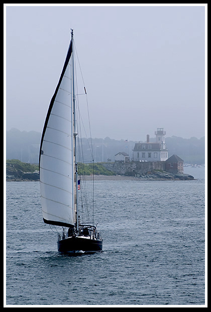 sailboat passes Rose Island light in the fog